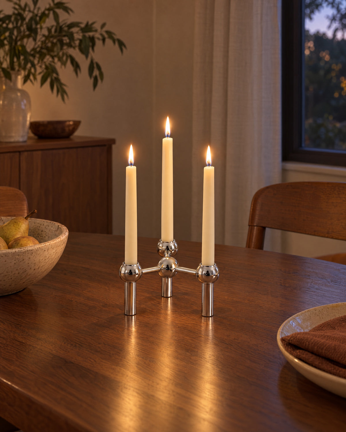 Silver: Orbit Stackable Metal Candlestick styled in a warm interior at dusk