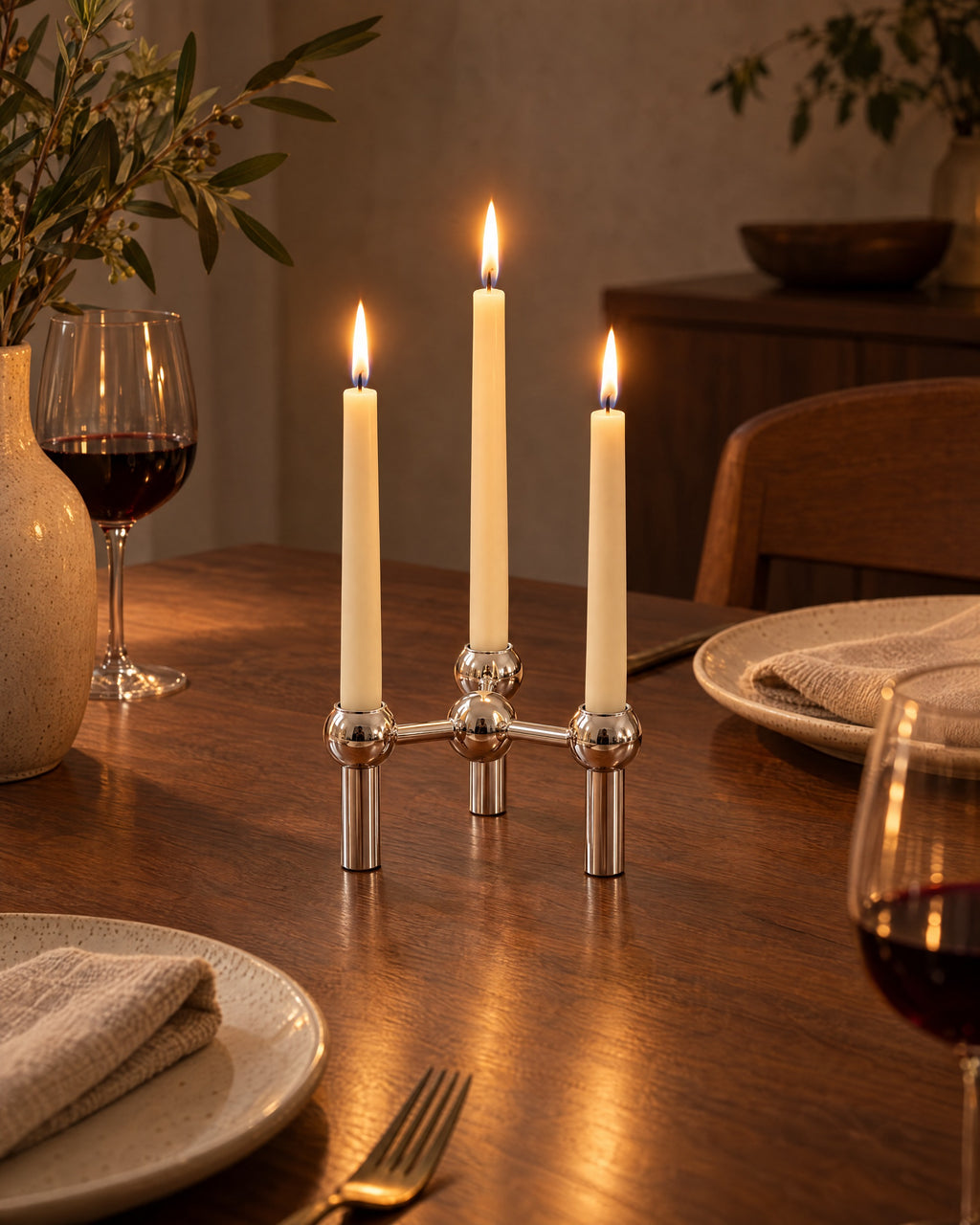 Silver: Orbit Stackable Metal Candlestick, lit, in a lived-in evening scene
