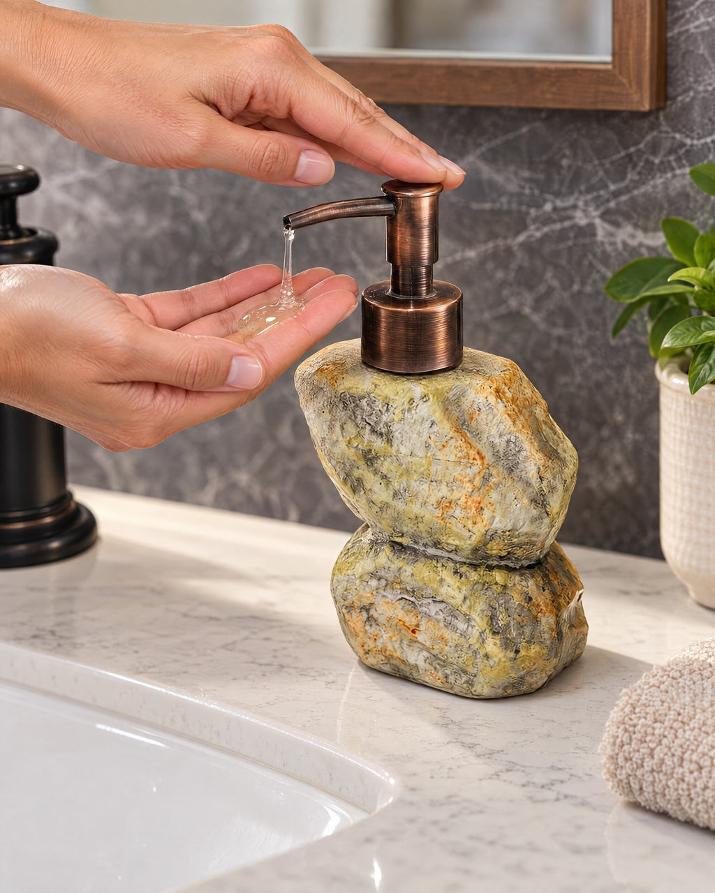 A hand pressing the pump of the Stacked Stone Soap Dispenser, Ceramic, Bronze Pump, 10.5 oz