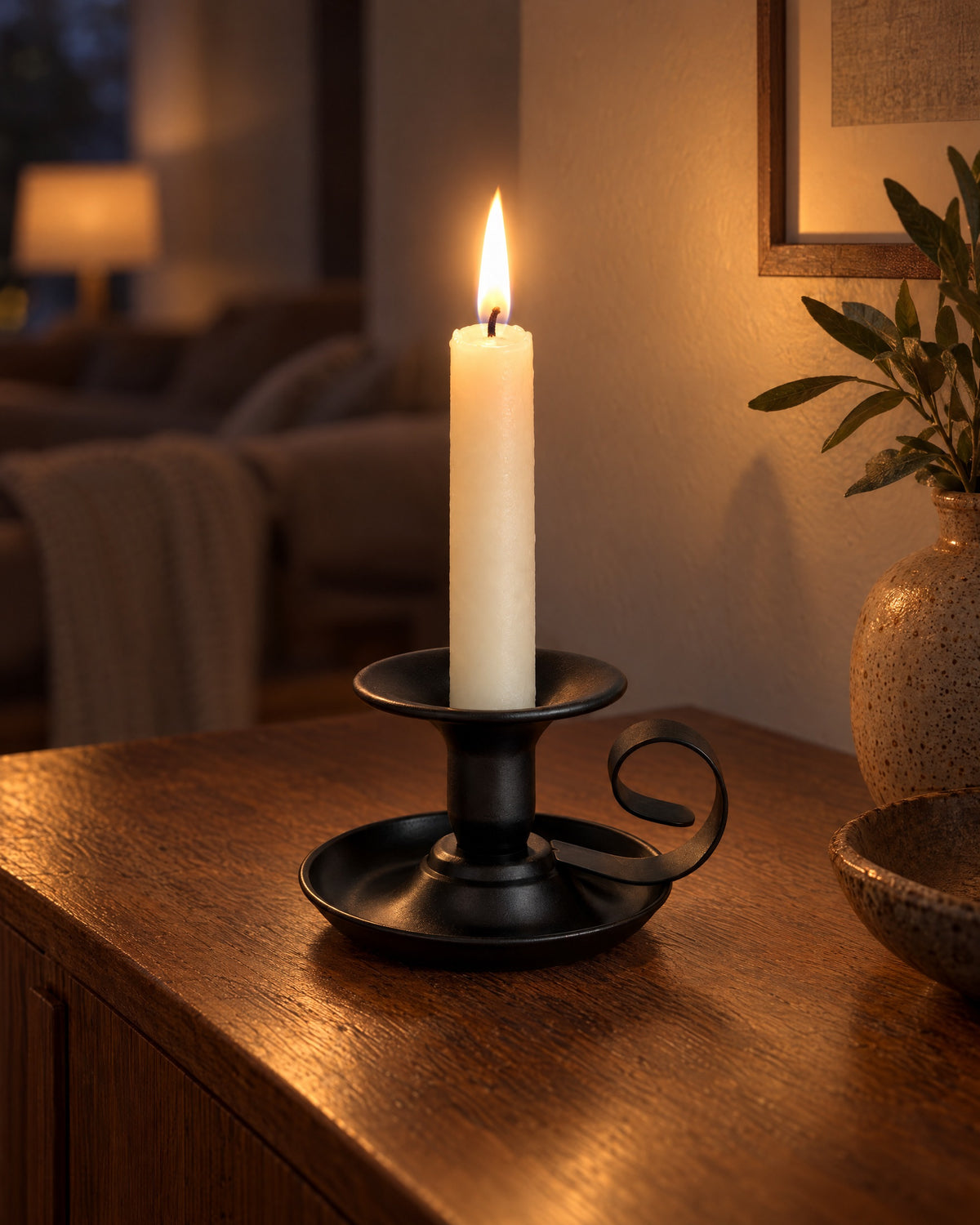 Tazza Iron Teacup Candle Holder with candles lit in the evening on a sideboard in a dim living room