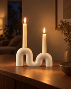 Twist Ceramic Double Candle Holder with candles lit in the evening on a sideboard in a dim living room