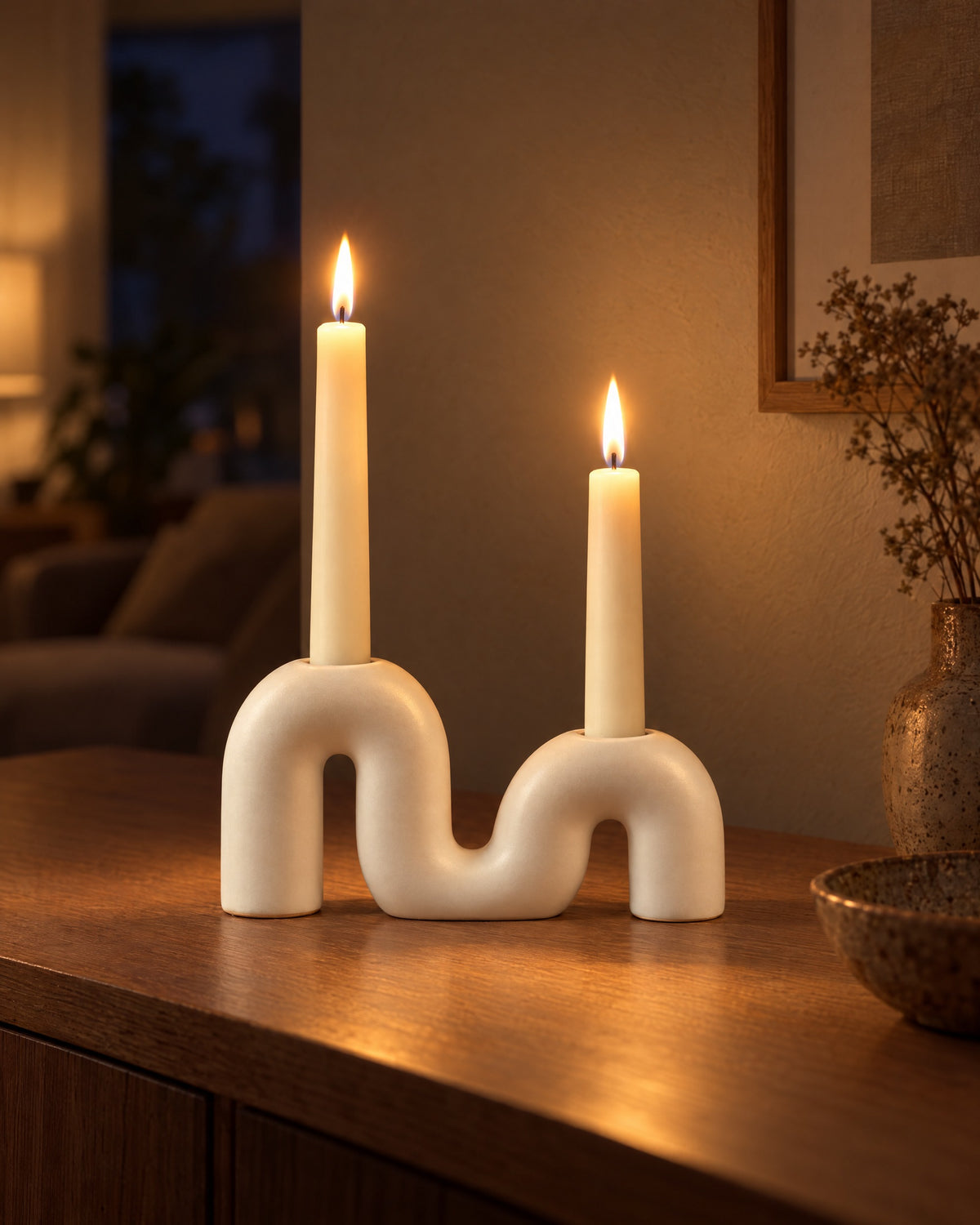 Twist Ceramic Double Candle Holder with candles lit in the evening on a sideboard in a dim living room