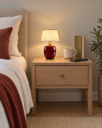 Burgundy: Vessel Cordless Ceramic Nightstand Lamp on a standard nightstand with a paperback, phone and mug for scale