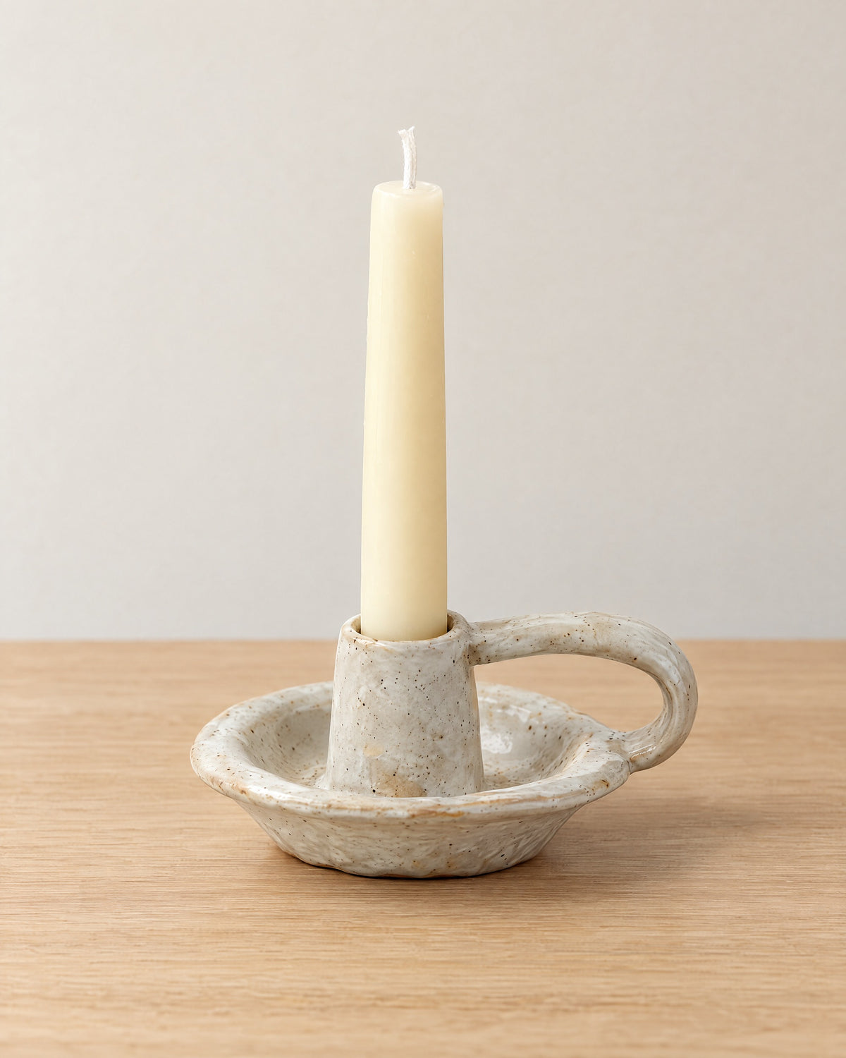 Wabi Speckled Ceramic Chamberstick on a light oak tabletop against a seamless studio backdrop