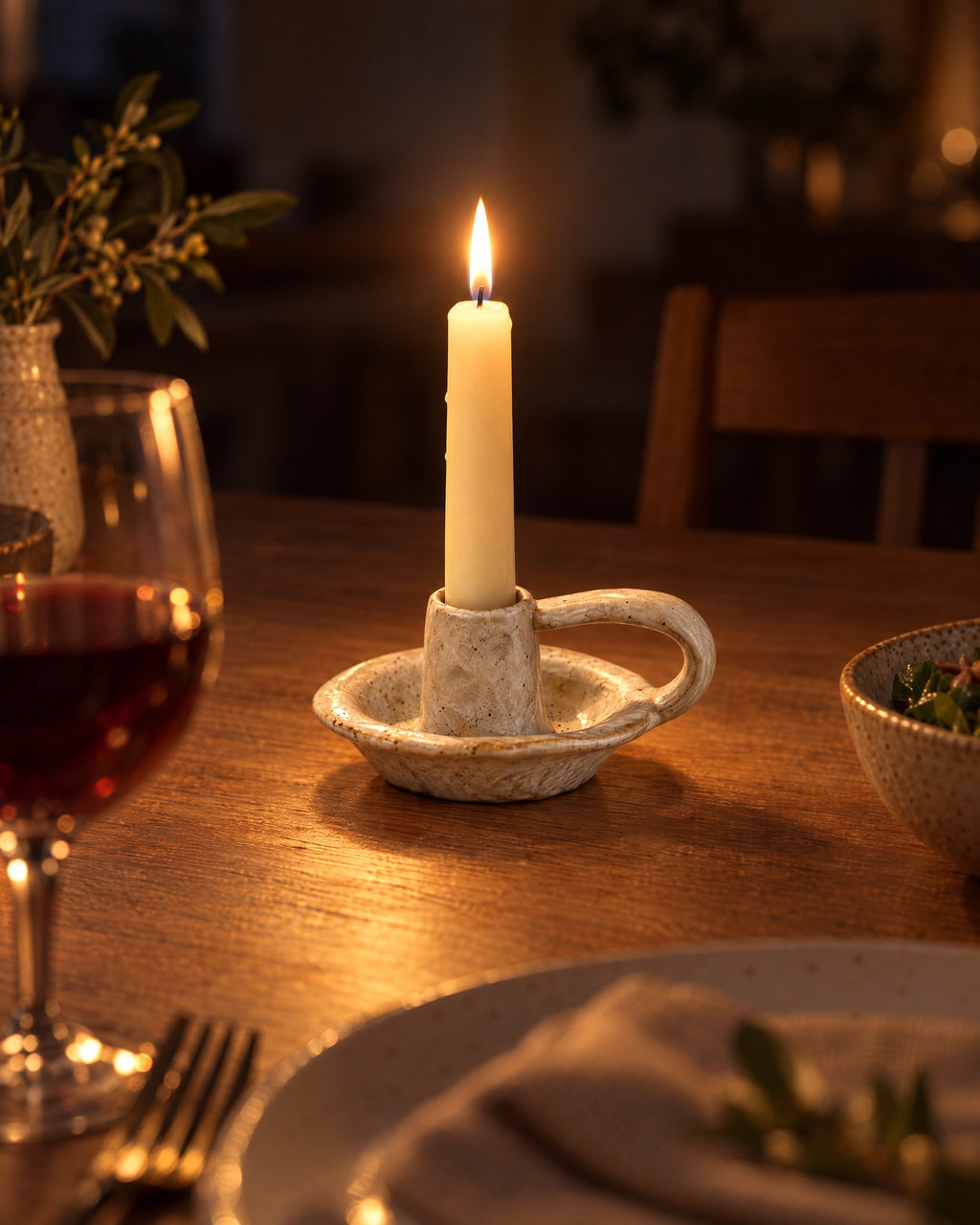 Wabi Speckled Ceramic Chamberstick with candles lit at night on a dinner table