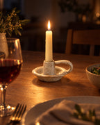 Wabi Speckled Ceramic Chamberstick with candles lit at night on a dinner table