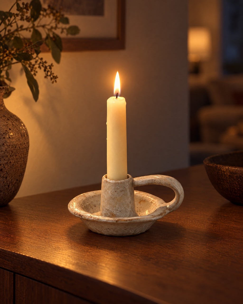 Wabi Speckled Ceramic Chamberstick with candles lit in the evening on a sideboard in a dim living room
