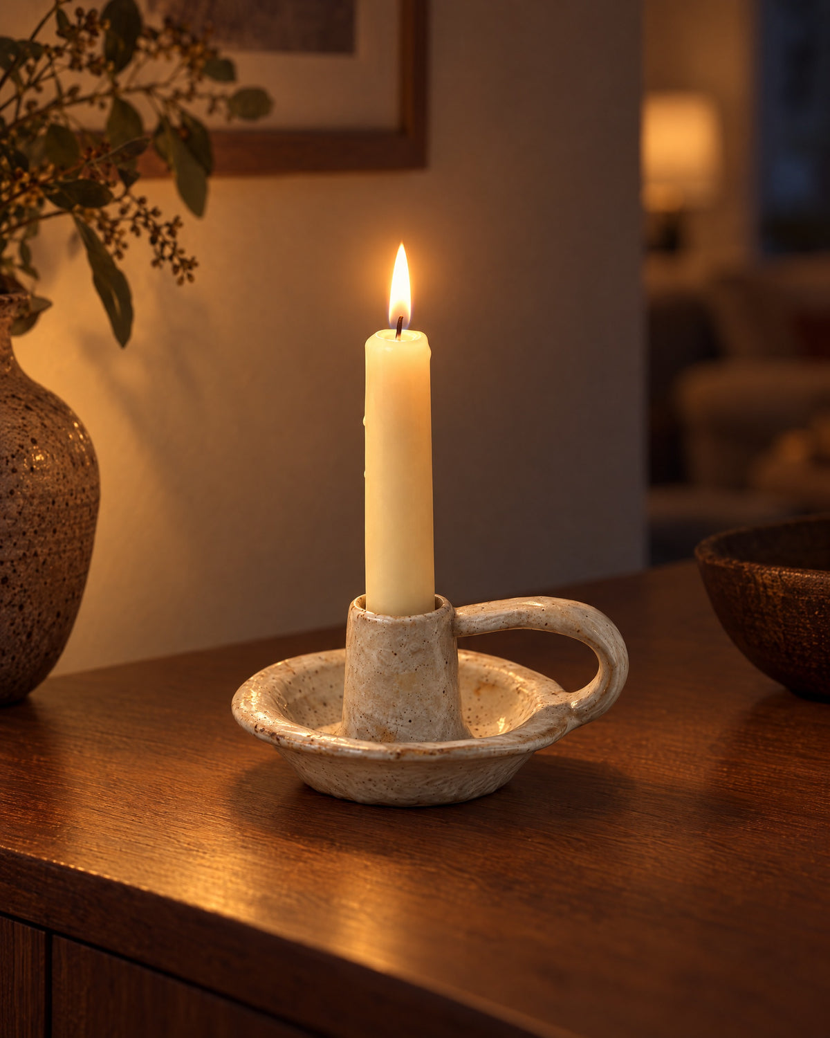 Wabi Speckled Ceramic Chamberstick with candles lit in the evening on a sideboard in a dim living room