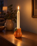 Zucca Pumpkin Ceramic Candle Holder with candles lit in the evening on a sideboard in a dim living room