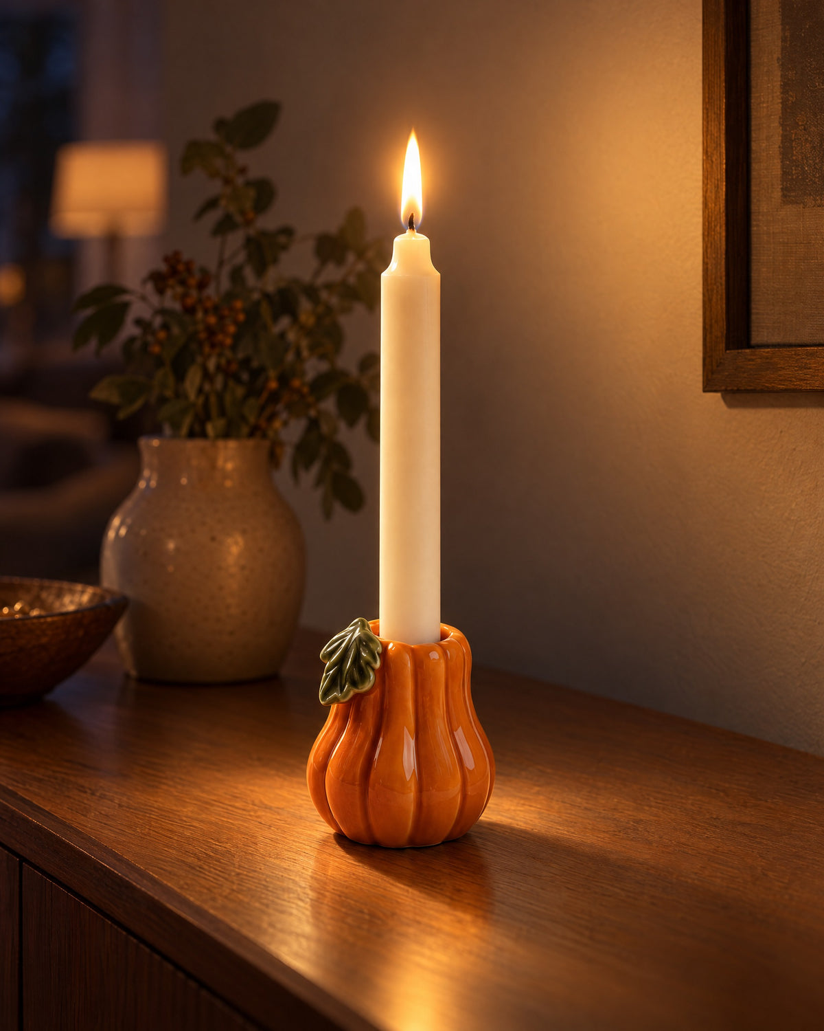 Zucca Pumpkin Ceramic Candle Holder with candles lit in the evening on a sideboard in a dim living room
